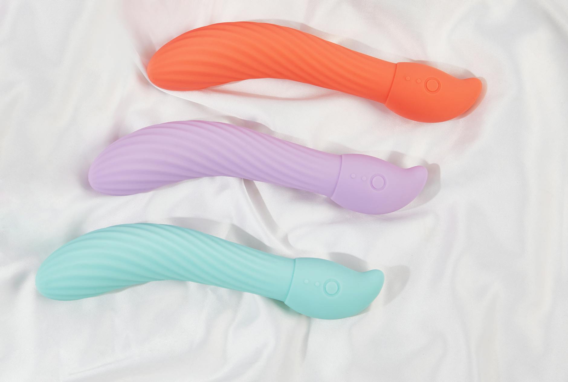 Woman holding blue and pink silicone vibrators in a contemplative pose