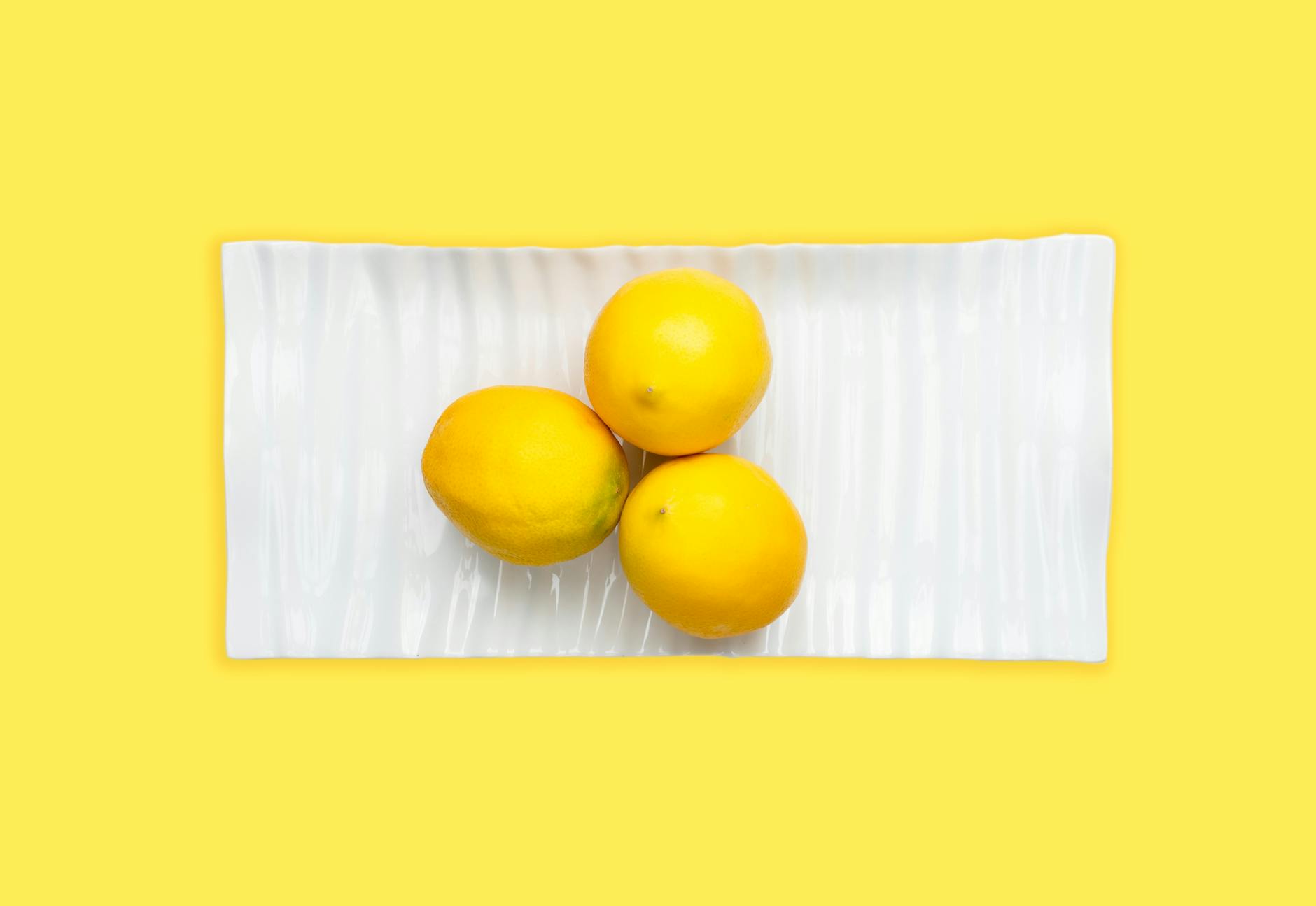 Hand holding a fresh lemon on soft pink background, symbolizing period wellness and self-care