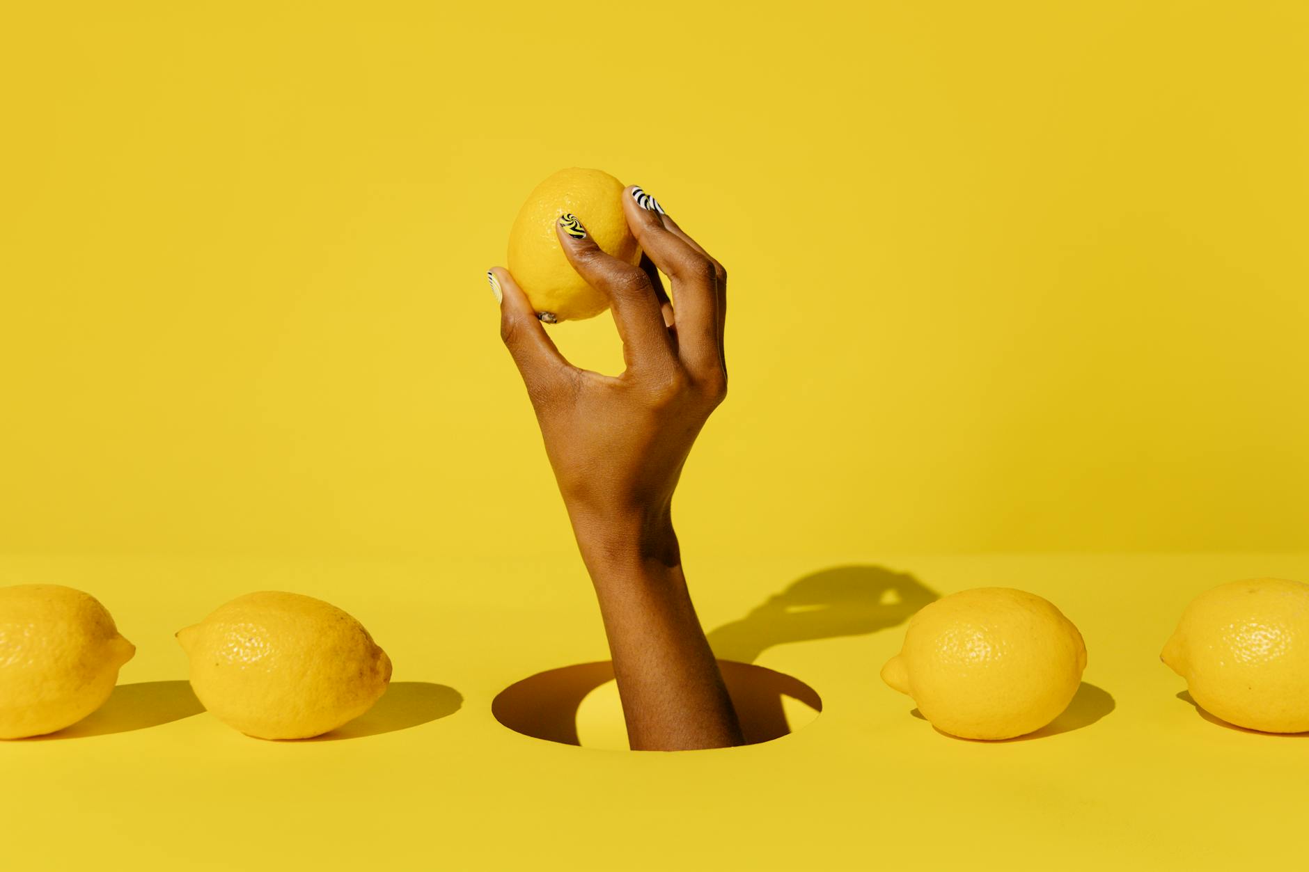 A hand holding a fresh lemon on a yellow background, symbolizing discovery and brightness