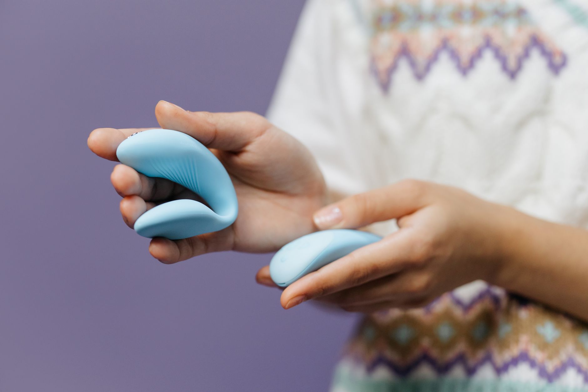 A hand holding a sleek lemon clitoral vibrator against a purple background, symbolizing intimate pleasure and connection.