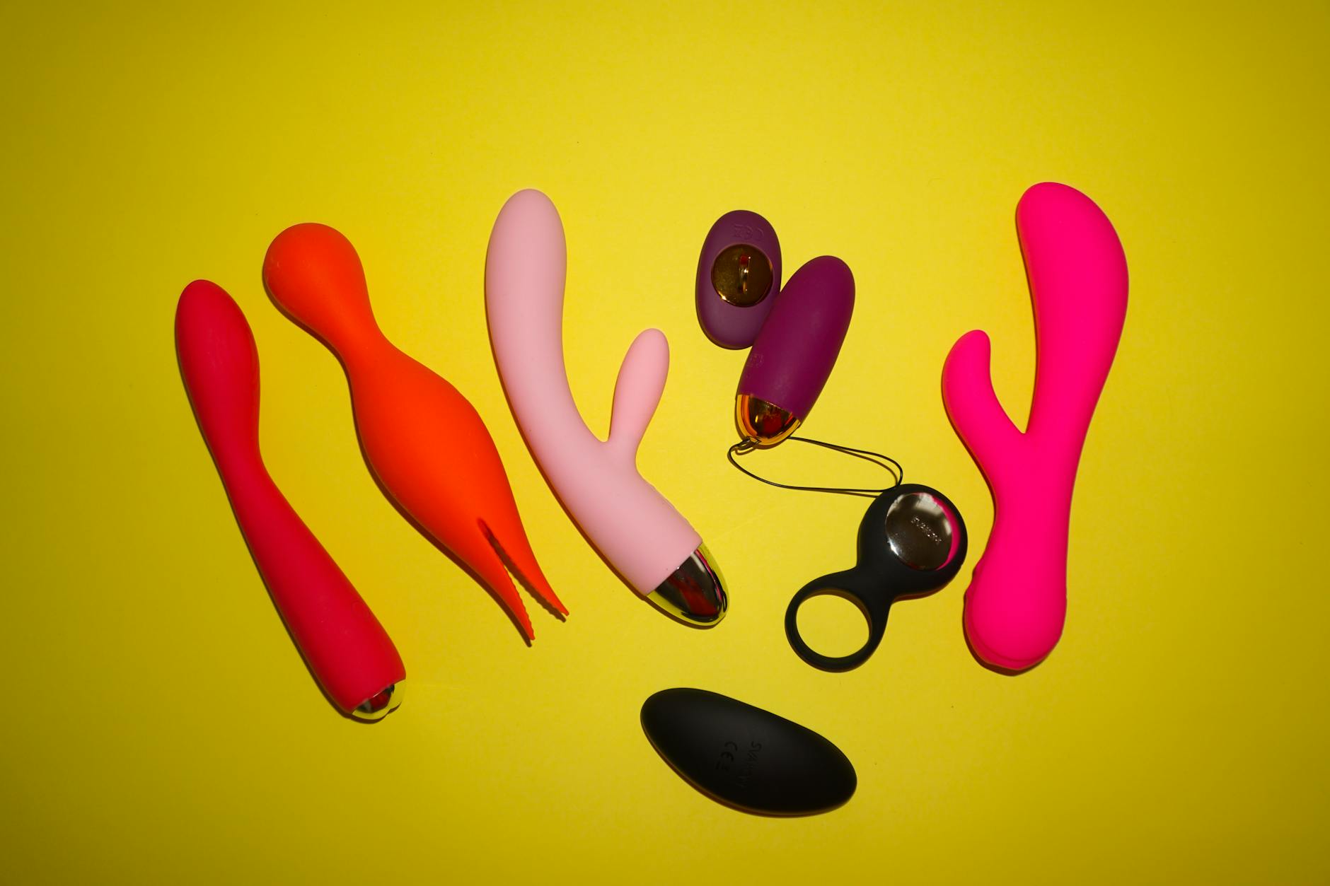 Blue clitoral vibrator surrounded by fresh flowers and citrus on a sunny yellow background